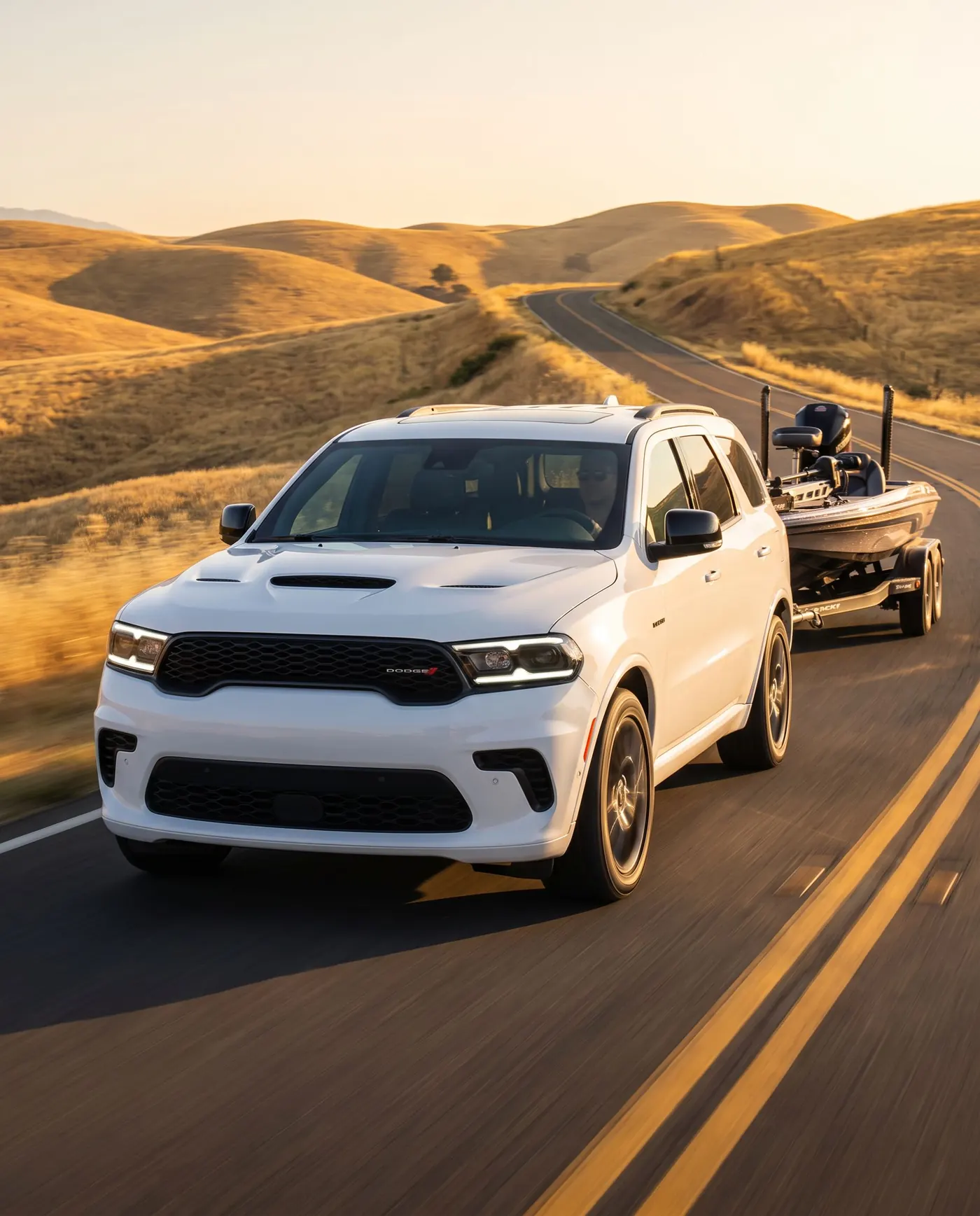 Dodge Durango towing a bass boat along golden California hills at sunrise