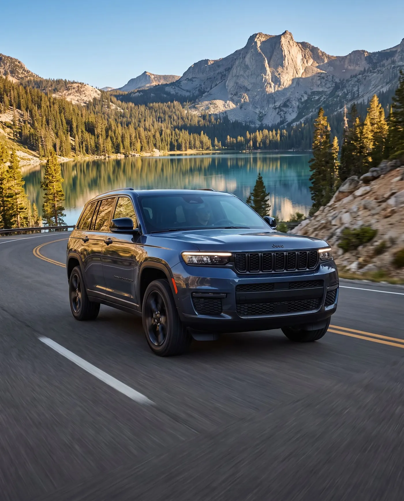 Jeep Grand Cherokee on a mountain highway above an alpine lake